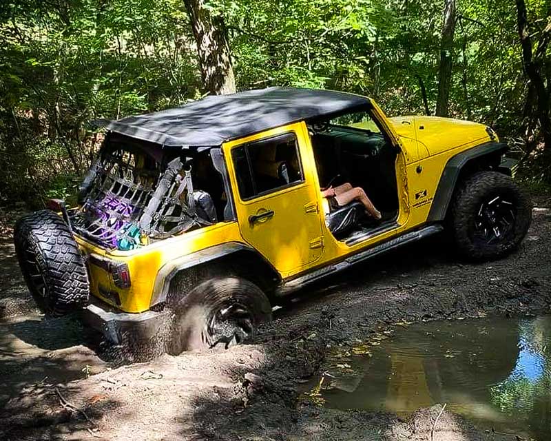 Yellow jeep diving through middy trail
