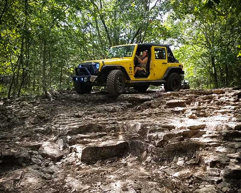 Yellow jeep driving down rocks