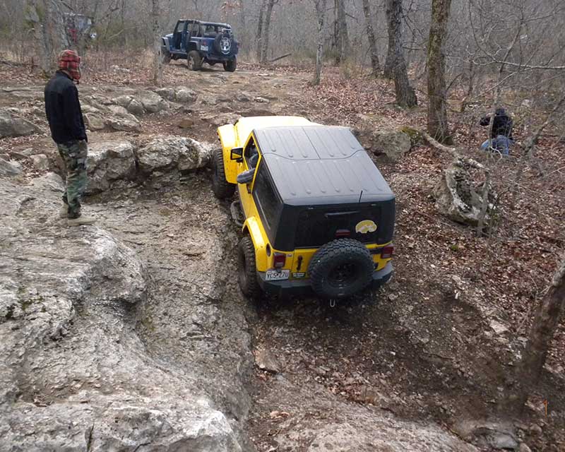 yellow jeep climbing up rocks
