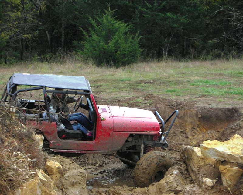 Red Jeep diving through mud and rocks