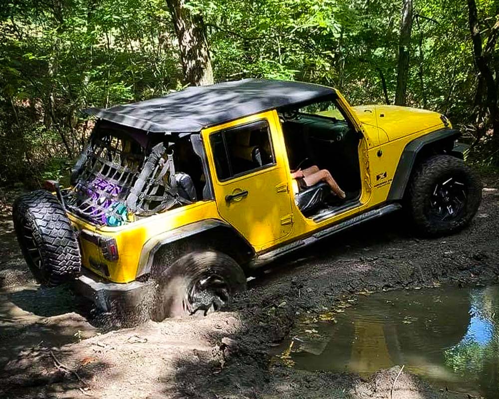 Yellow jeep diving through mud