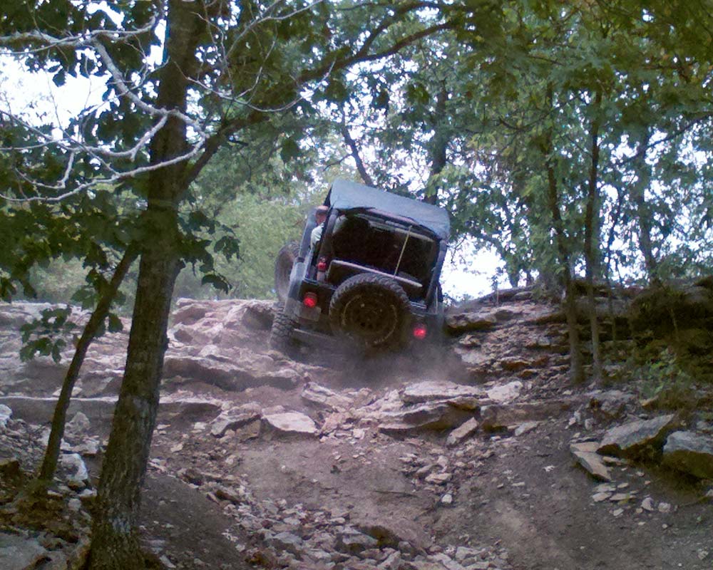 Jeep driving over the top of rocky climb