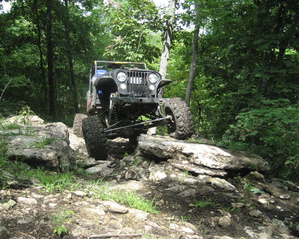 Jeep driving over large rock